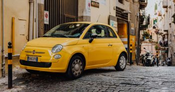 Yellow modern little car, Fiat 500, parked on a street in Naples